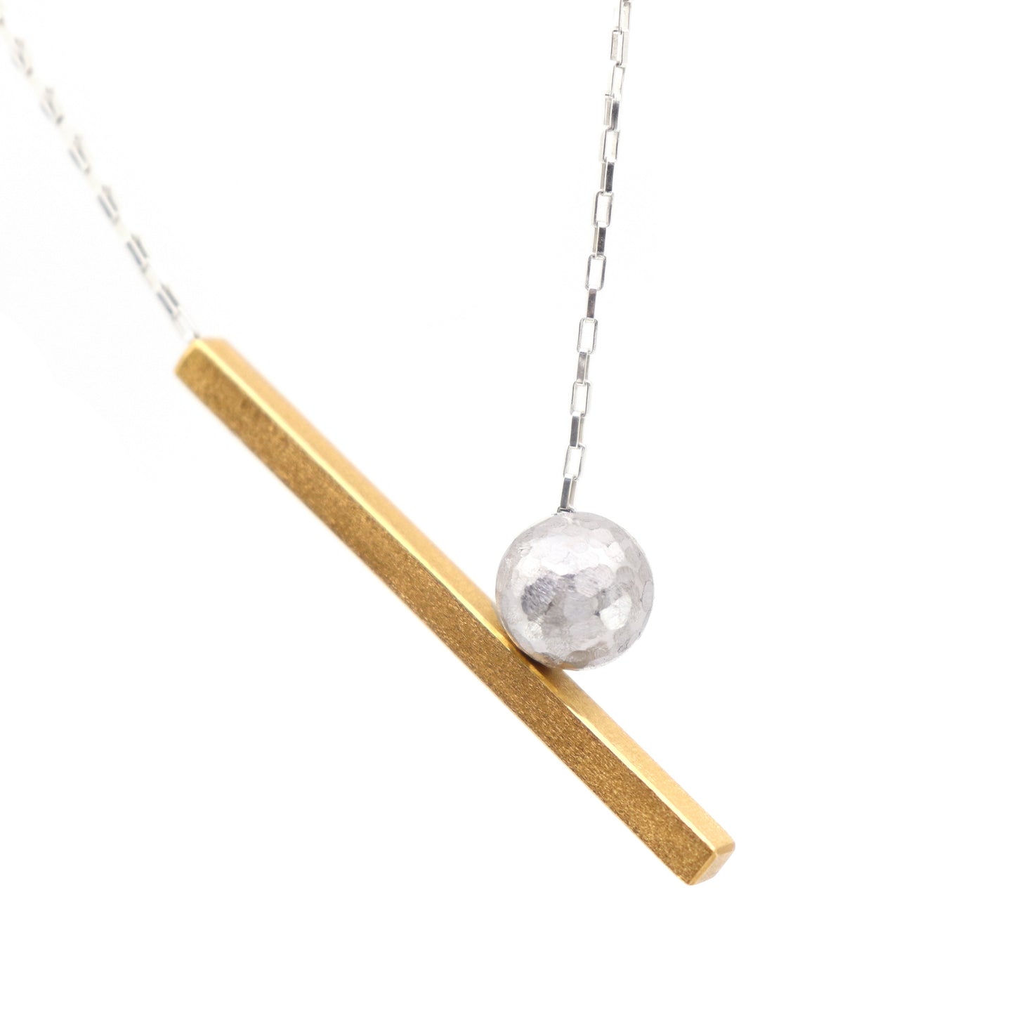 Necklace with a gold bar and silver sphere pendant on a white background