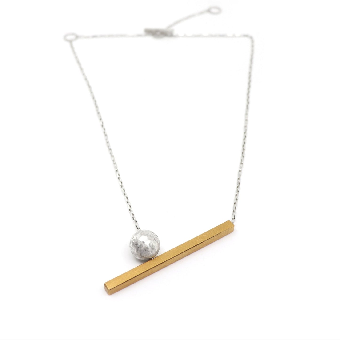 Necklace with a gold bar and silver sphere pendant on a white background
