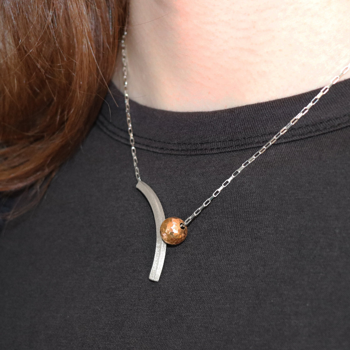 silver arch with gold bead necklace worn against black top