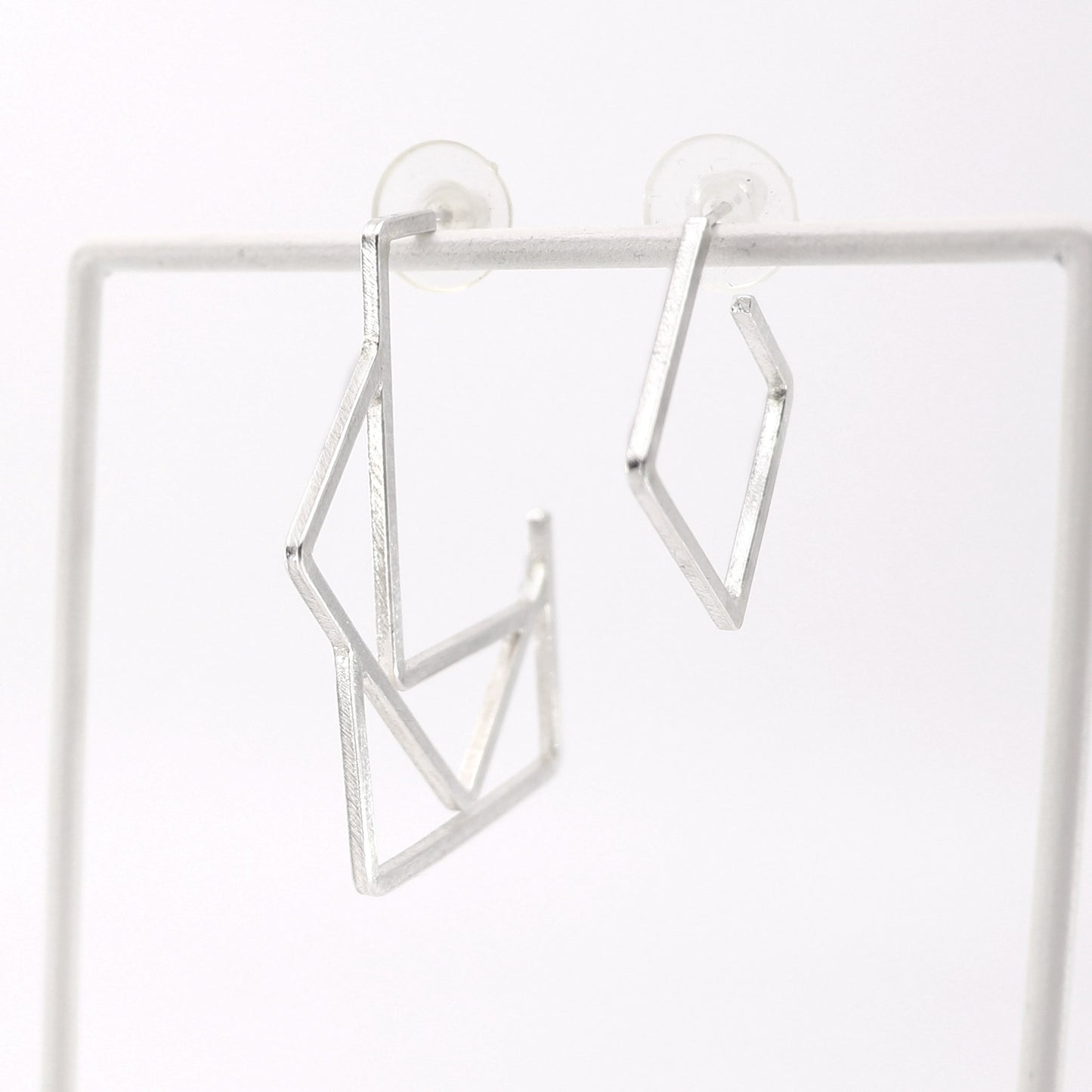 Silver geometric hoop earrings on a white background