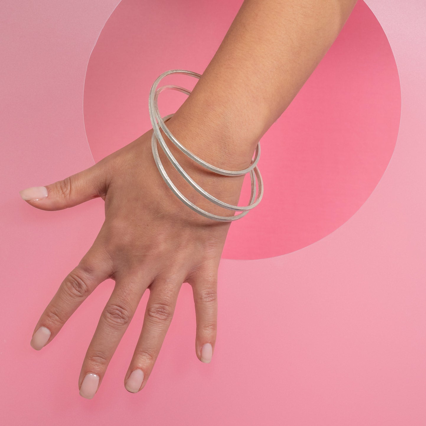 silver statement bangle modelled on pink background