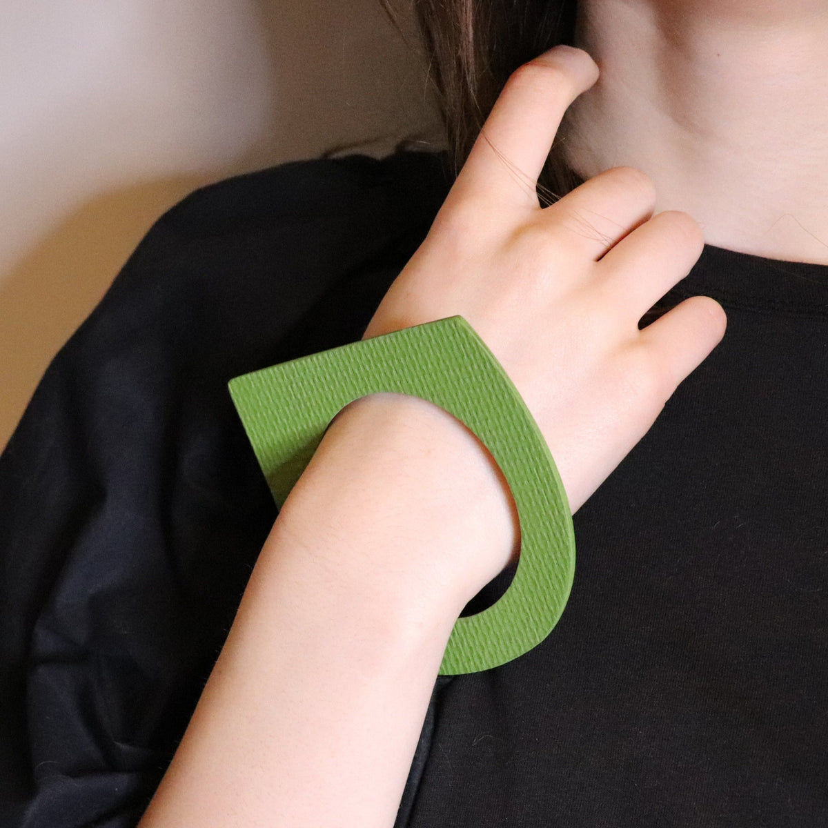 person wearing green linoleum bangle in geometric shape
