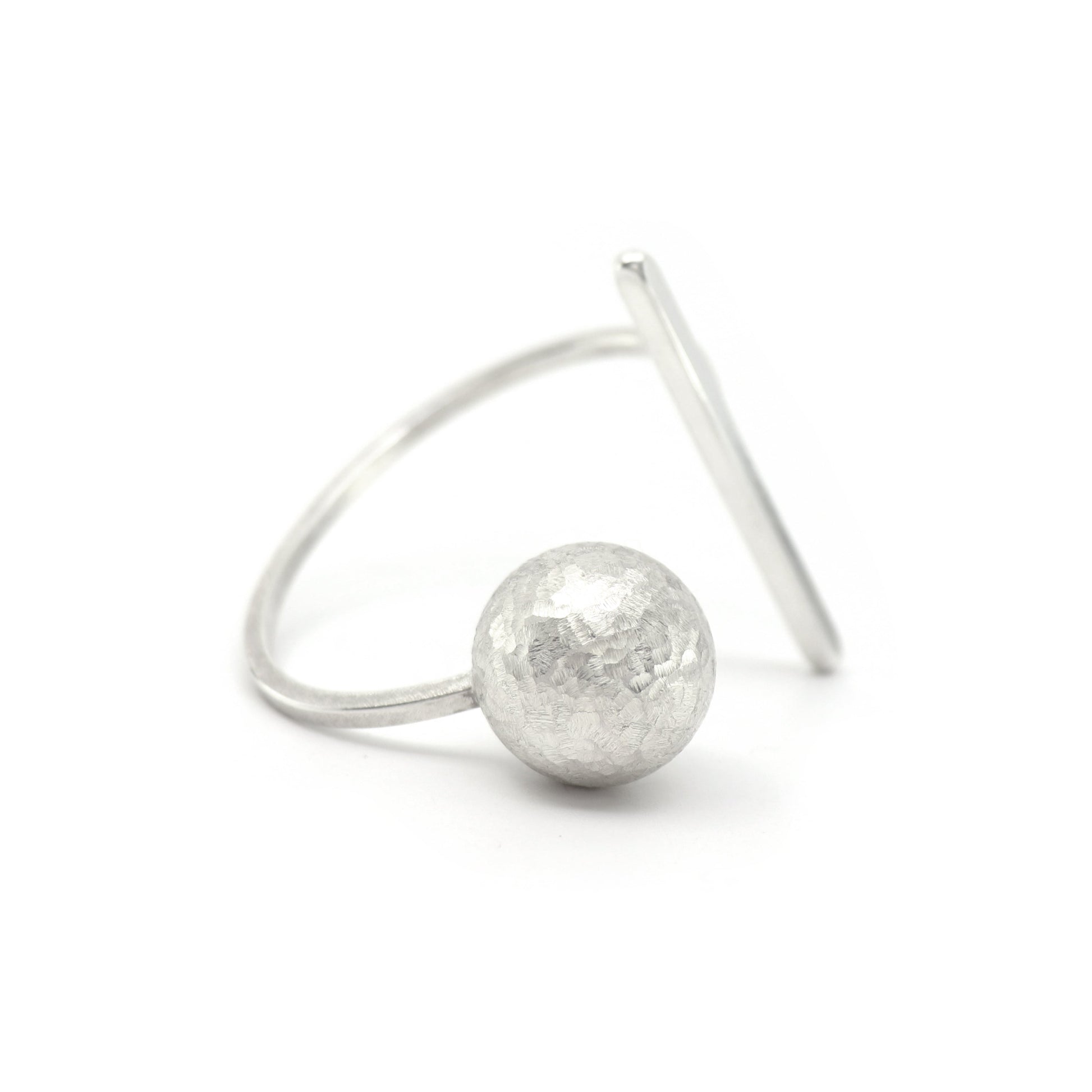 A minimalist sterling silver architectural cuff bangle featuring a hammered-textured spherical bead and a flat, angled bar, photographed on a seamless white background.