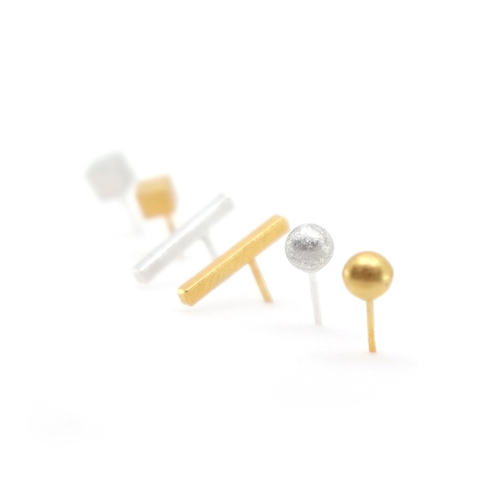 Set of gold, silver, and white earrings on a white background