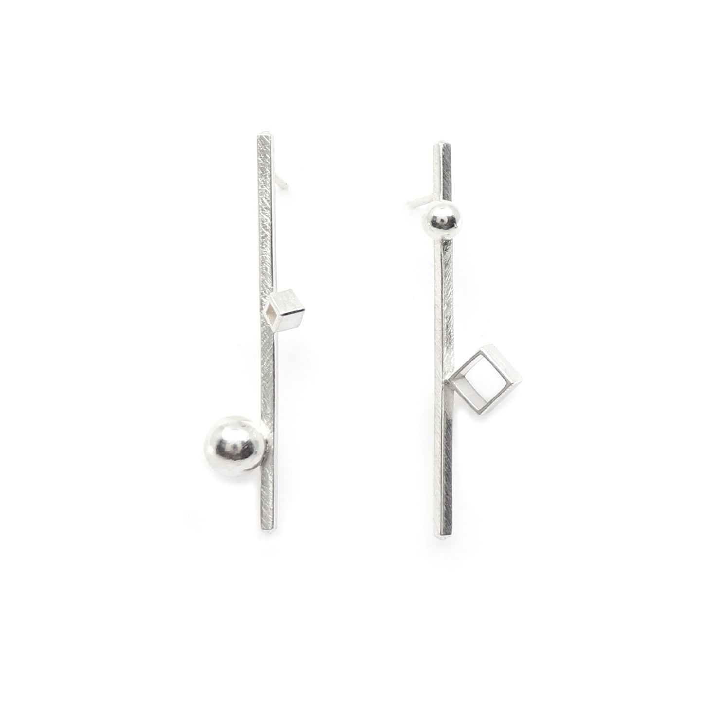 A pair of architectural sterling silver geometric earrings on a clean white background. One earring features a vertical textured bar with a spherical bead at the bottom and a small square at the top, while the other features a similar vertical bar with a square at the top and a larger square at the bottom.