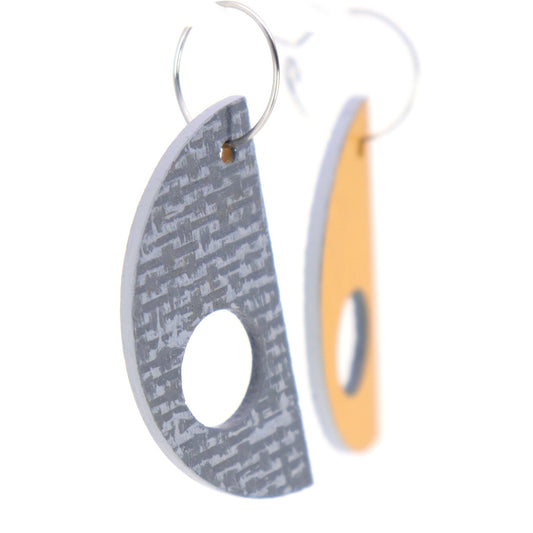 Pair of earrings with one gray textured and one orange smooth design on a white background