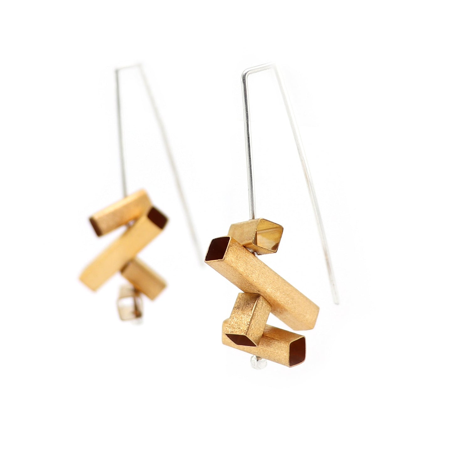 Gold and silver geometric architectural earrings on a white background