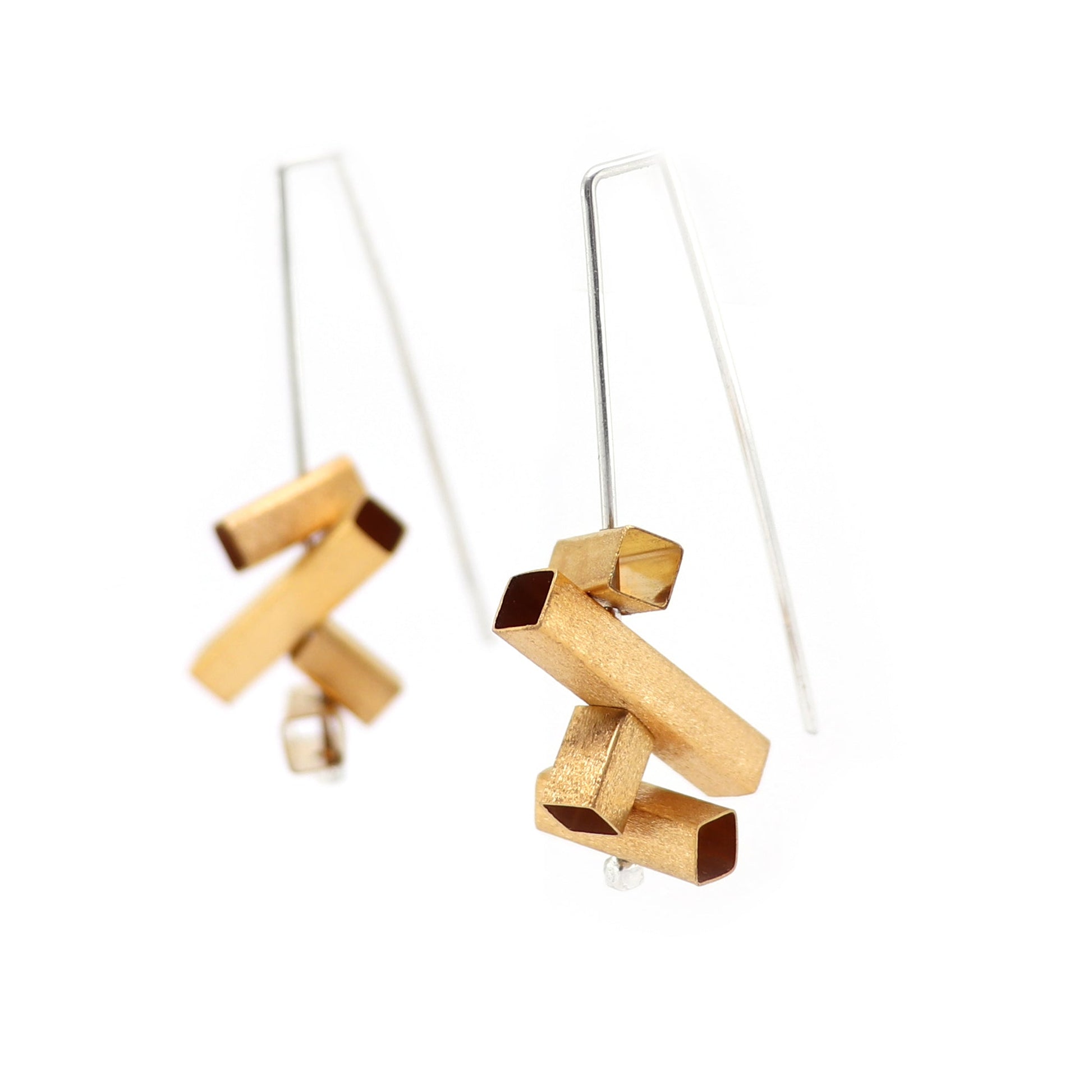 Gold and silver geometric architectural earrings on a white background