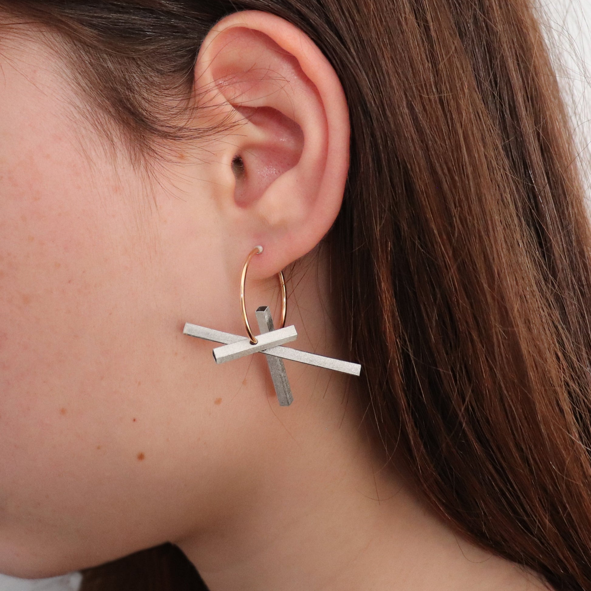 silver and gold hoop earring worn by brunette