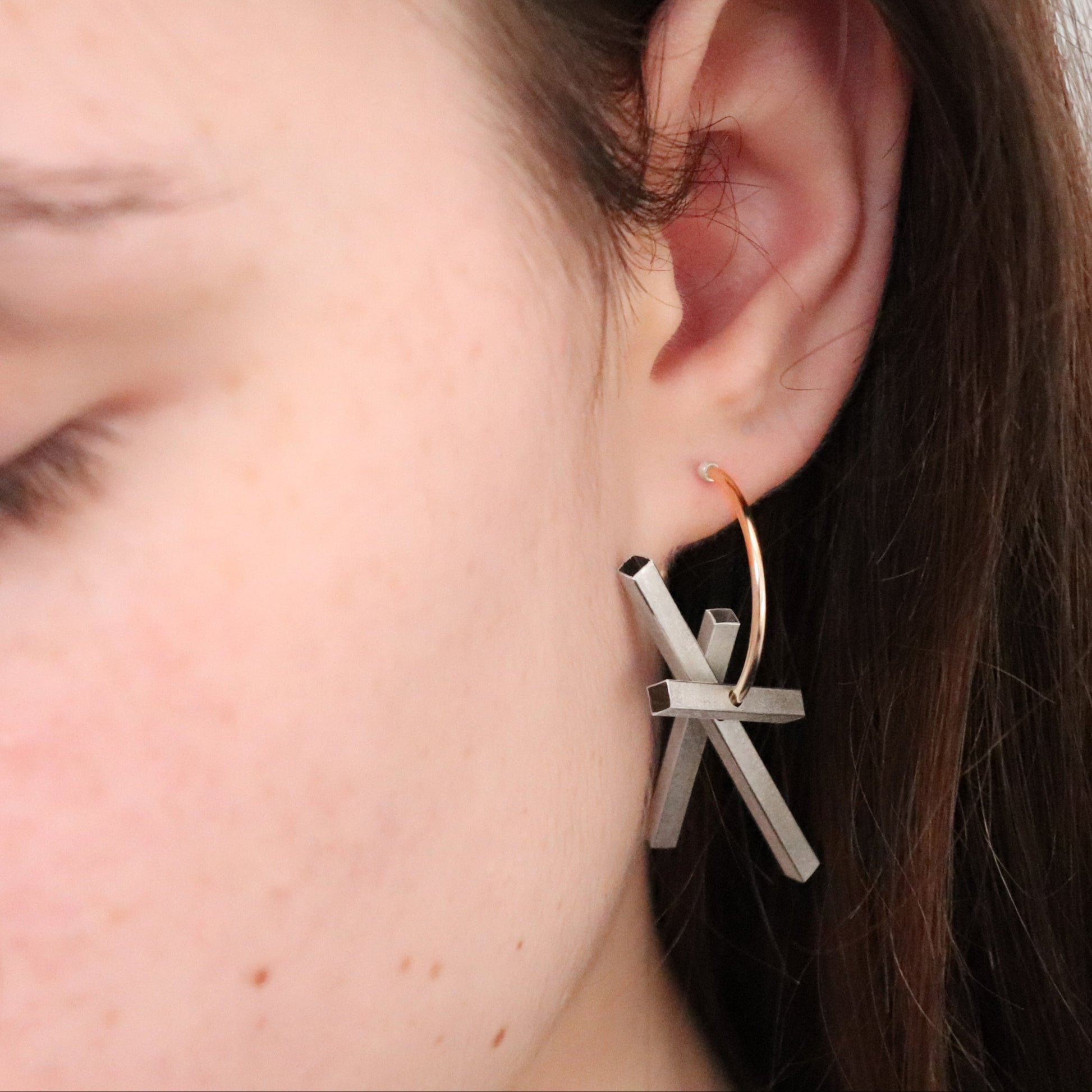 silver rectangle components on gold hoop geometric earring worn by female