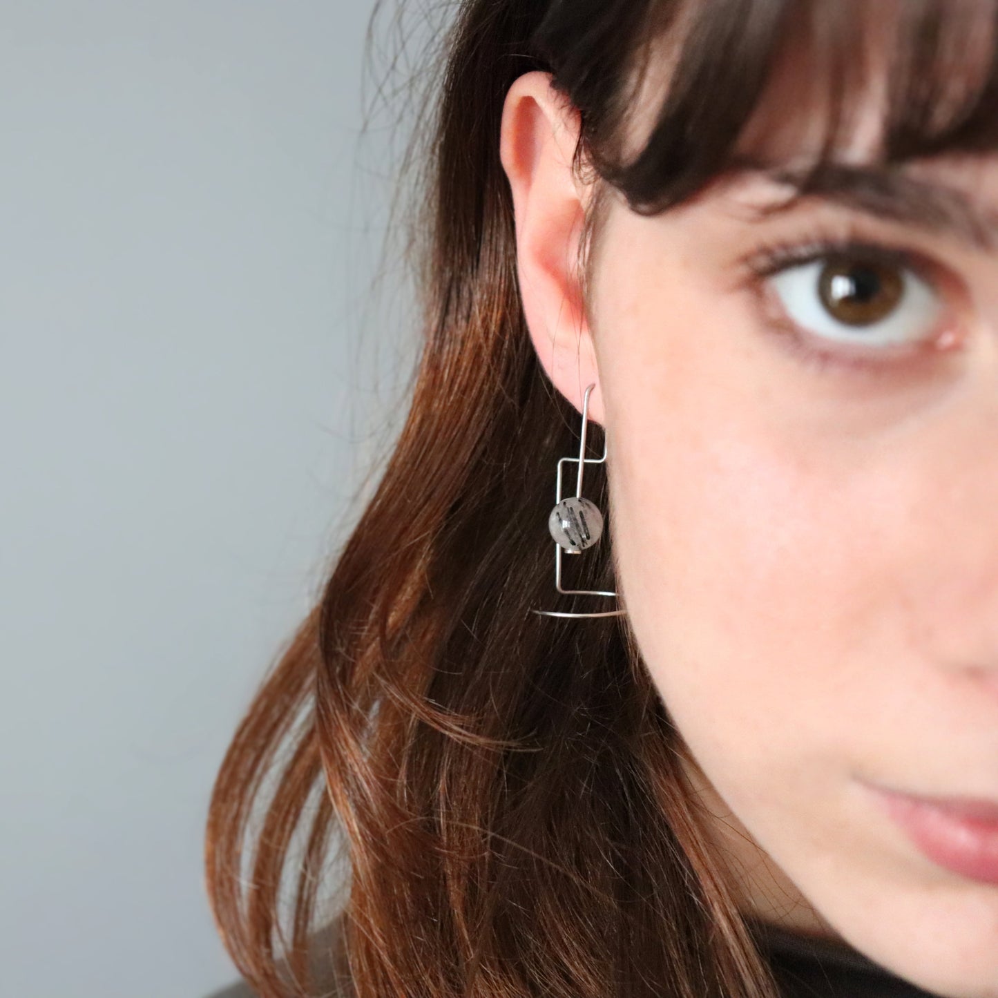 Close-up of a person wearing a silver earring with a blurred background
