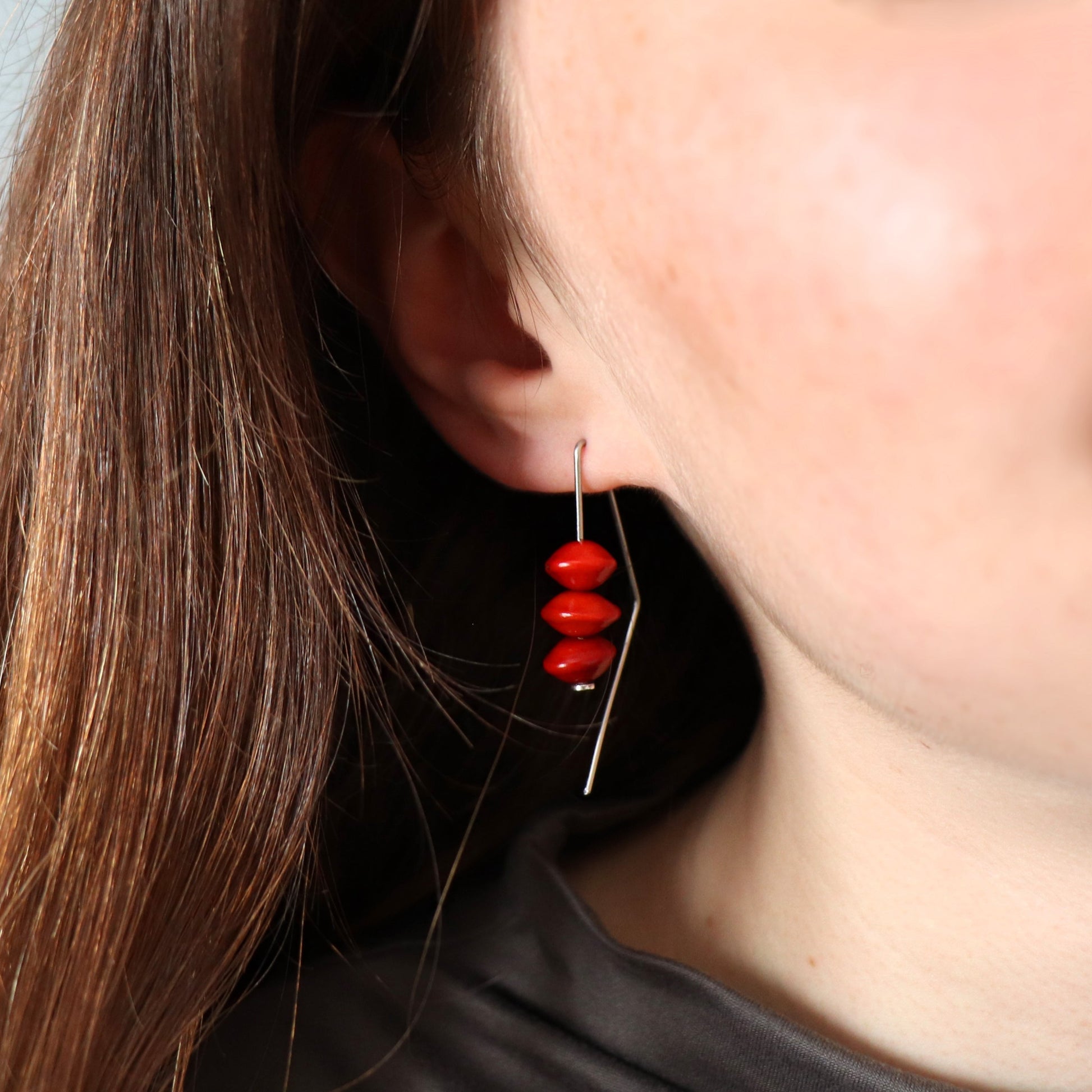 Close-up of a person wearing a red beaded earring with a blurred background