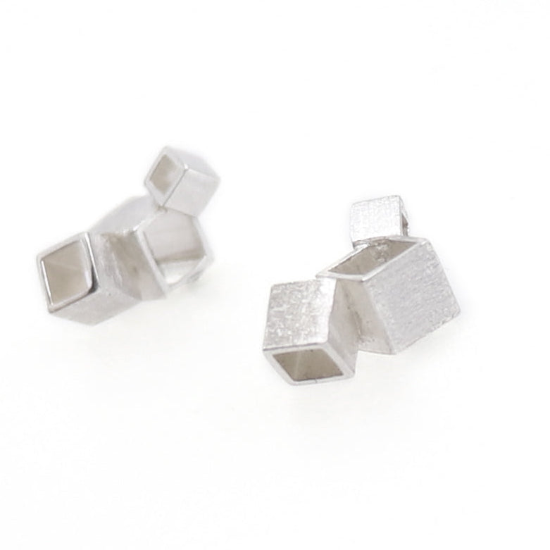 Pair of silver geometric earrings on a white background