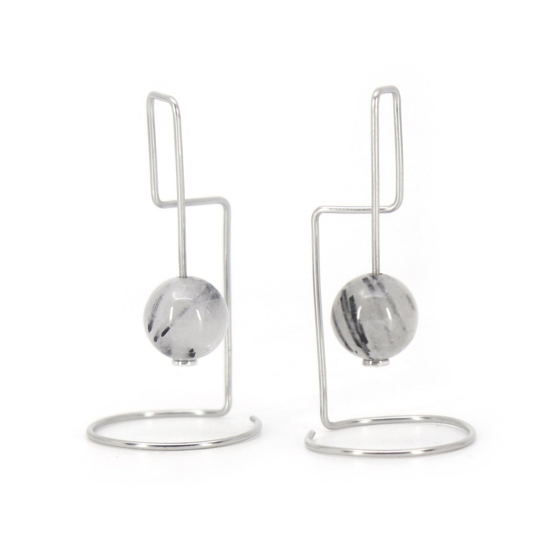 Pair of architectural earrings with rutilated agate beads on a white background