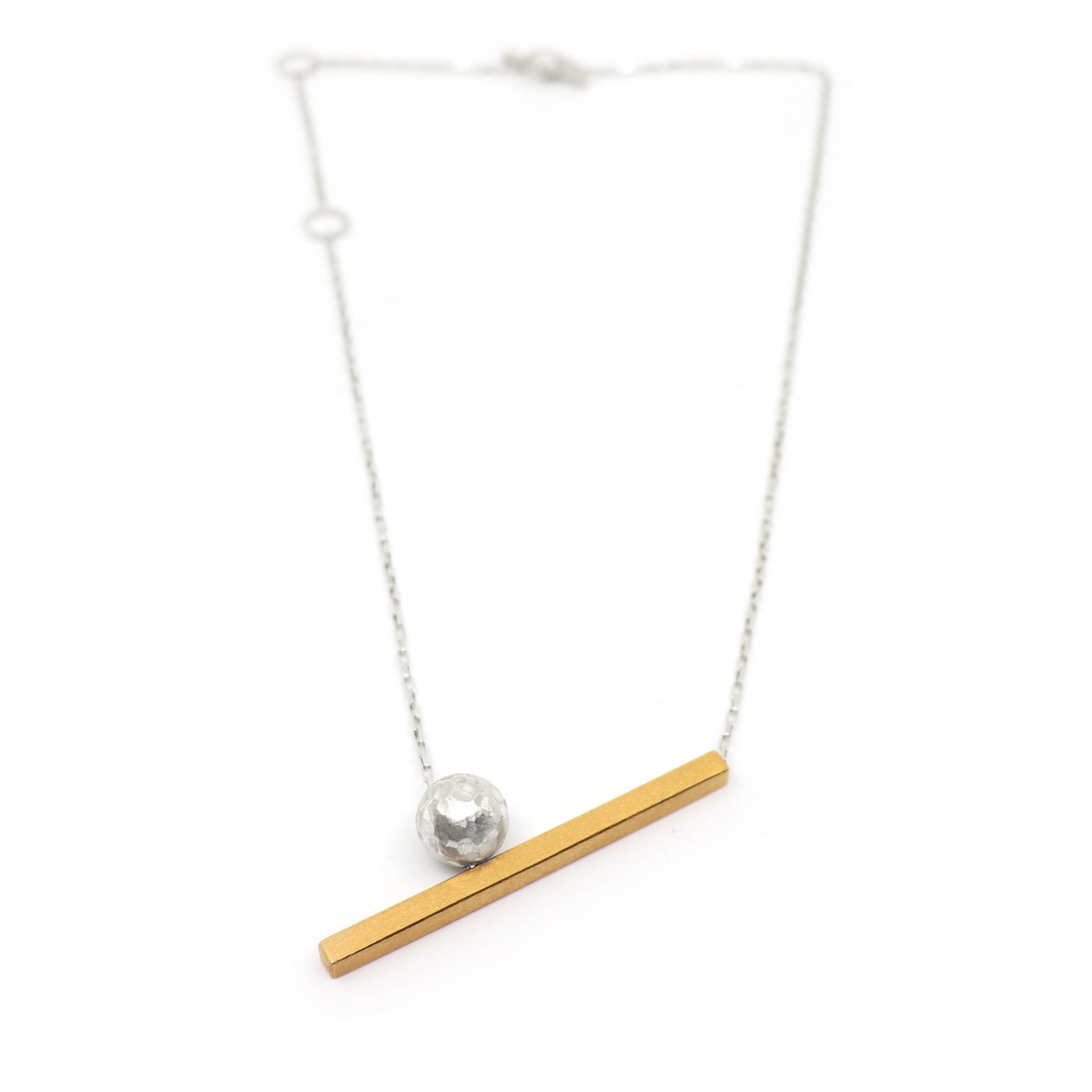 Necklace with a gold bar and silver sphere pendant on a white background