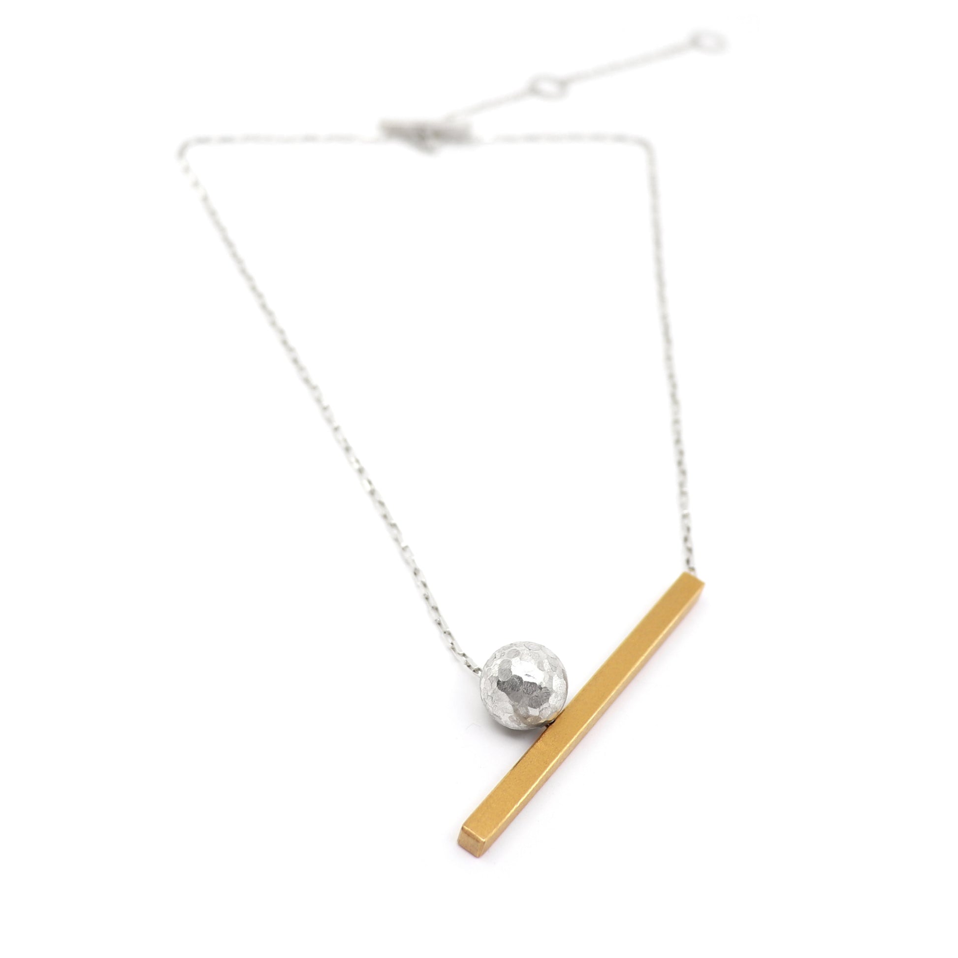 Necklace with a gold bar and silver sphere pendant on a white background