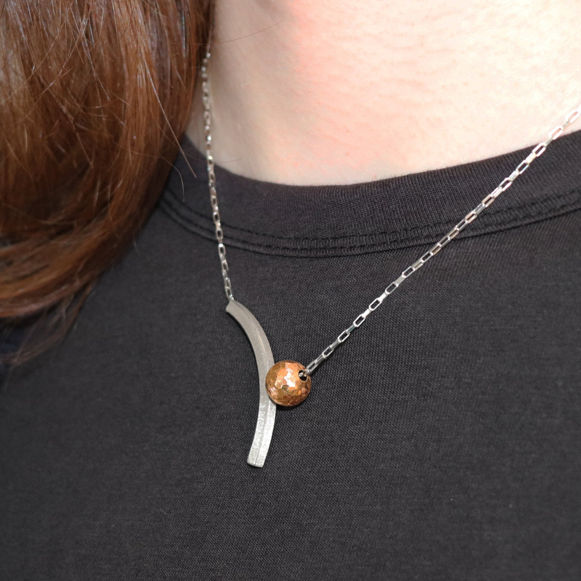 silver arch with gold bead necklace worn against black top