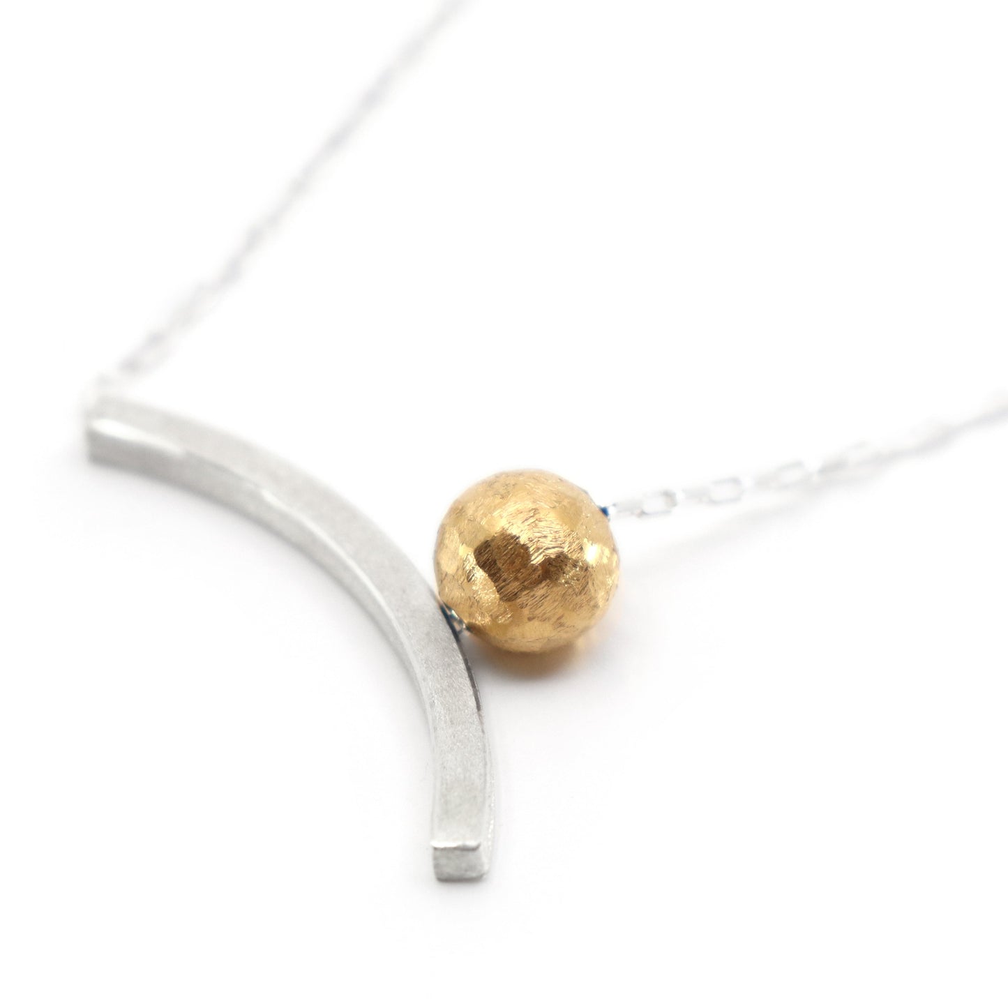 Necklace with a gold bead and silver curved bar on a white background