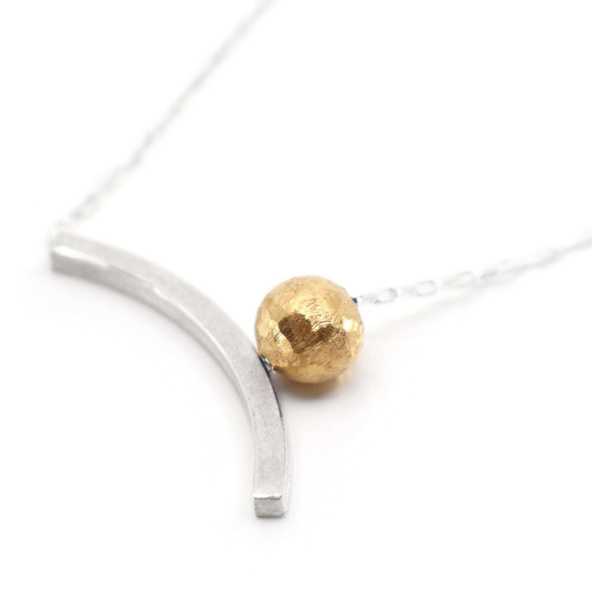 Necklace with a gold bead and silver curved bar on a white background