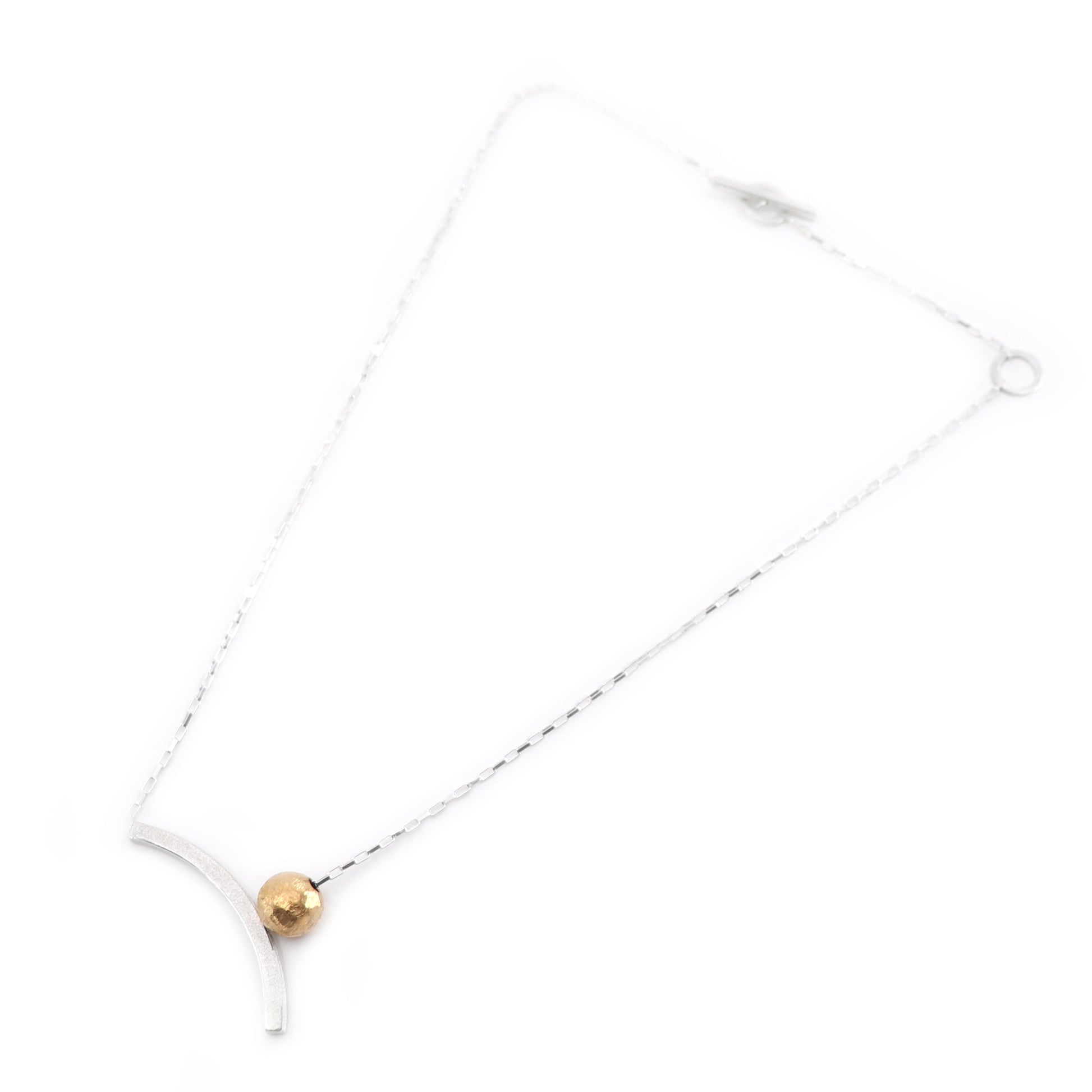 Necklace with a gold bead and curved silver on a white background