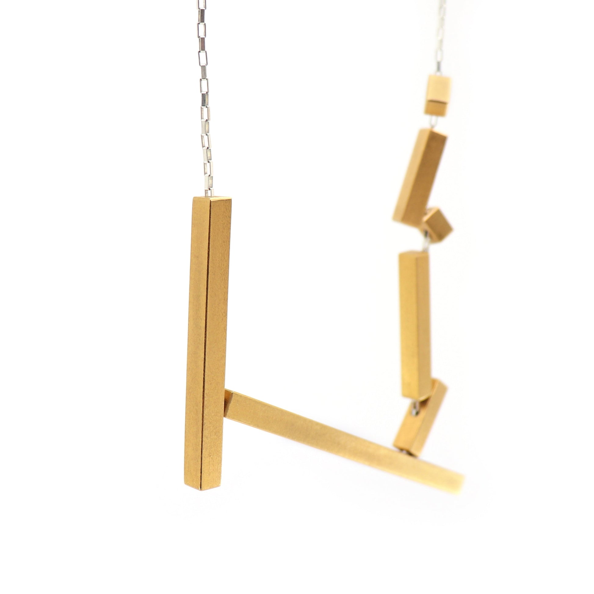 Gold metal statement necklace with geometric design on silver chain a white background