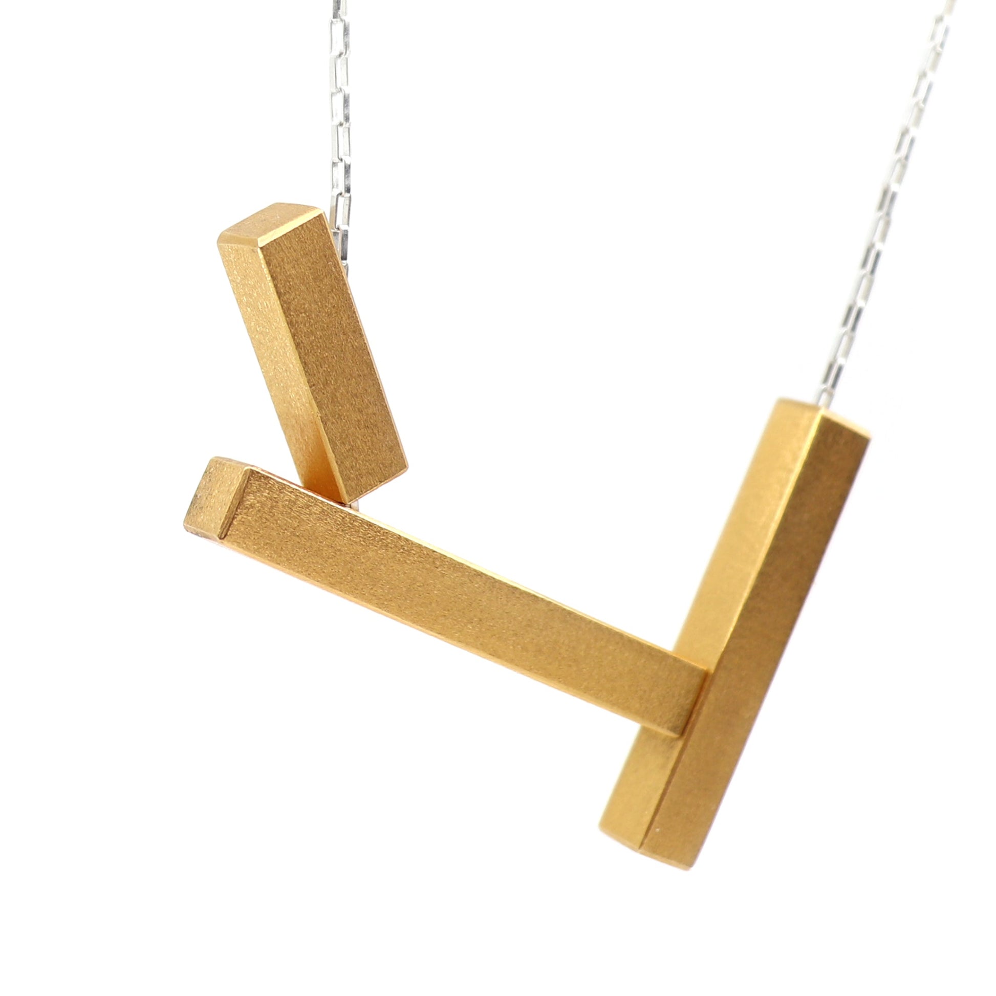Gold necklace with a geometric pendant on a white background