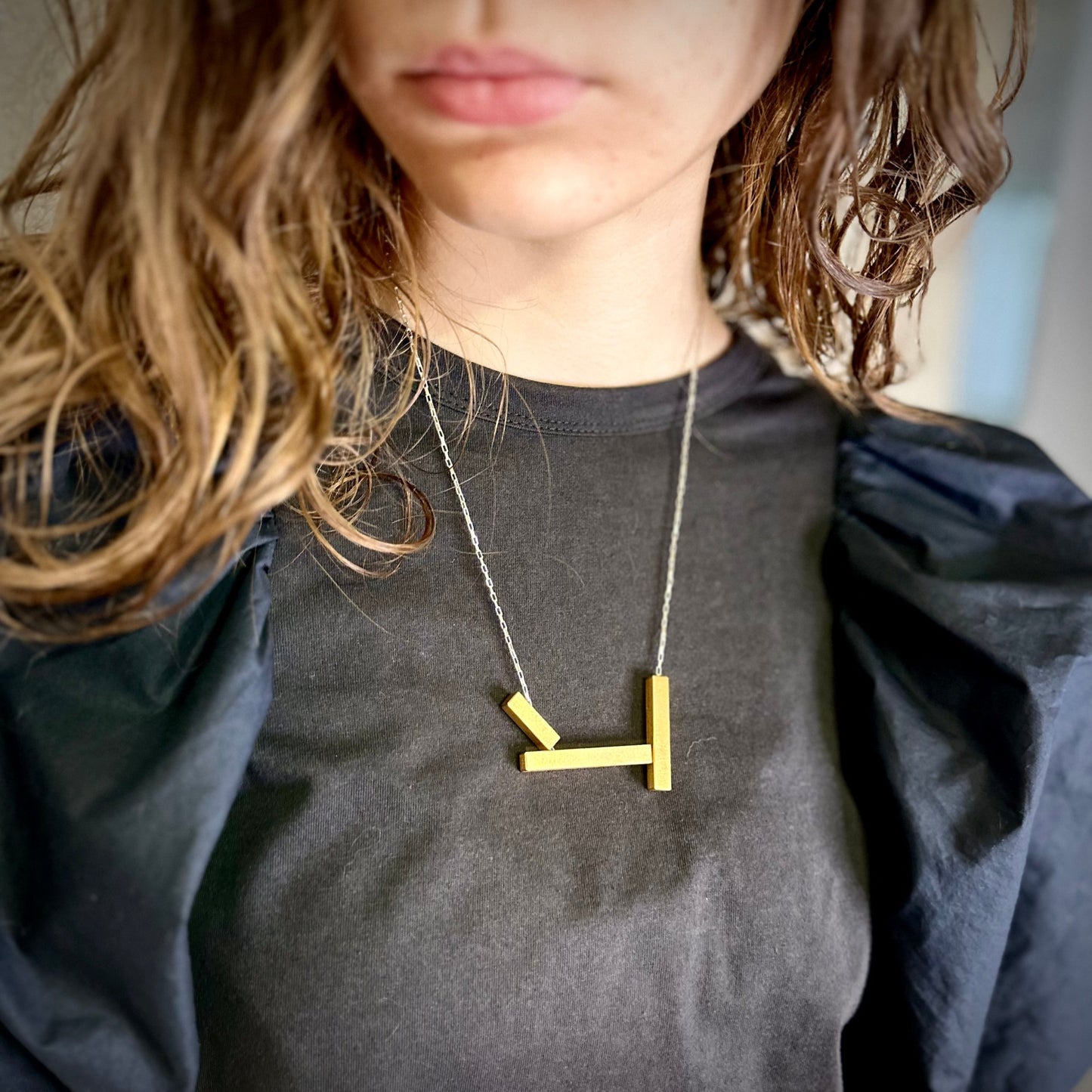 Geometric landslide necklace in gold with silver chain, worn long. 