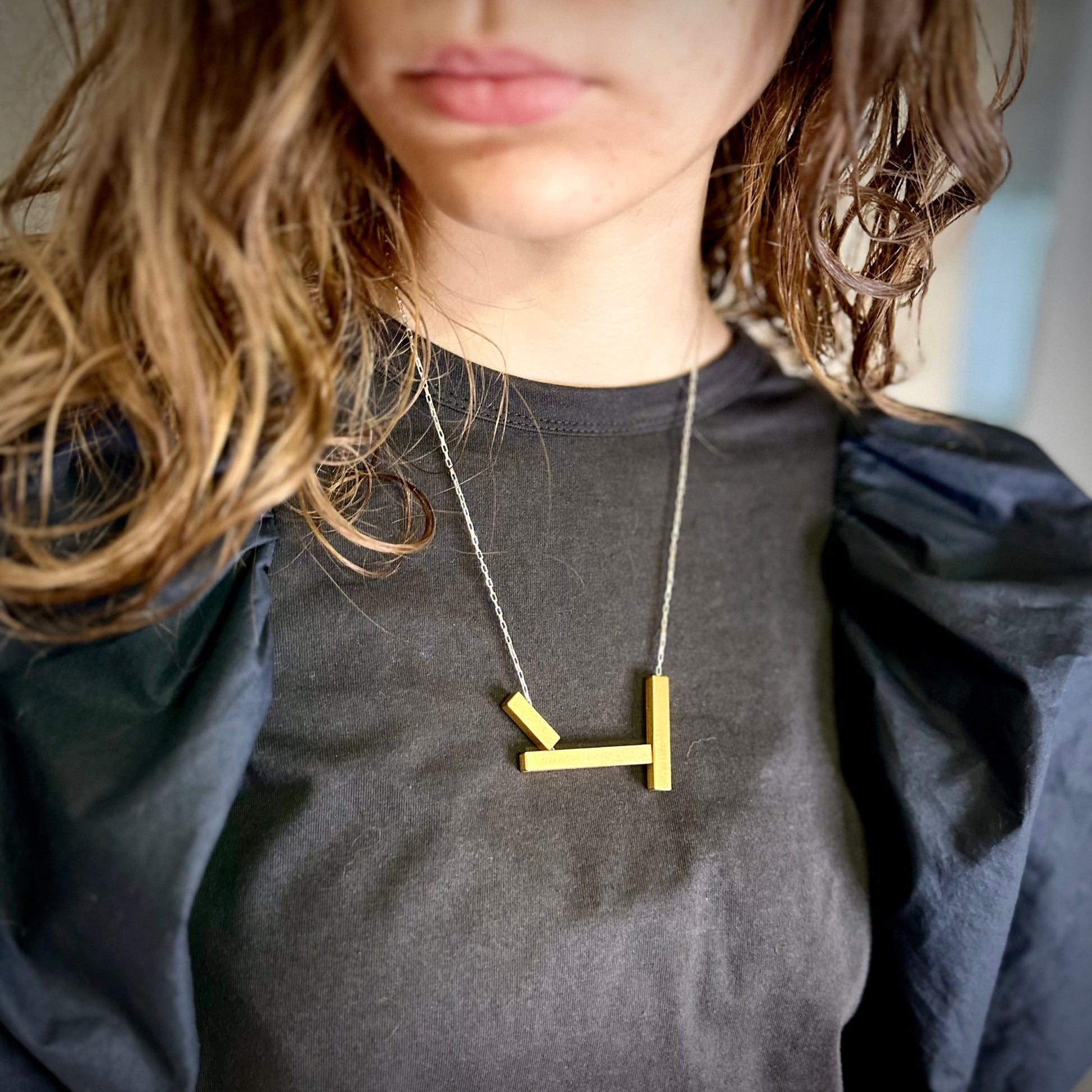 Geometric landslide necklace in gold with silver chain, worn long. 