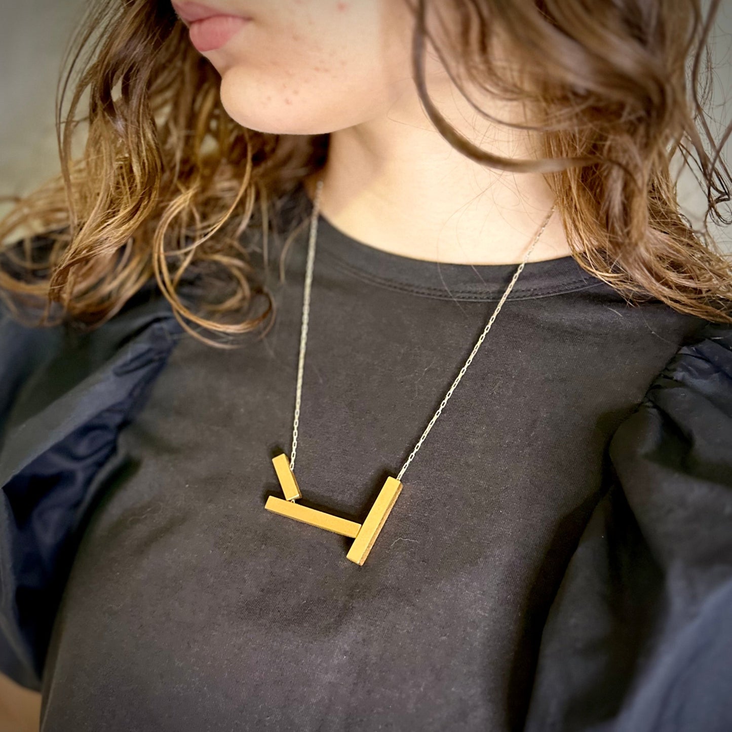 Architectural landslide necklace in gold with silver chain, worn long. 