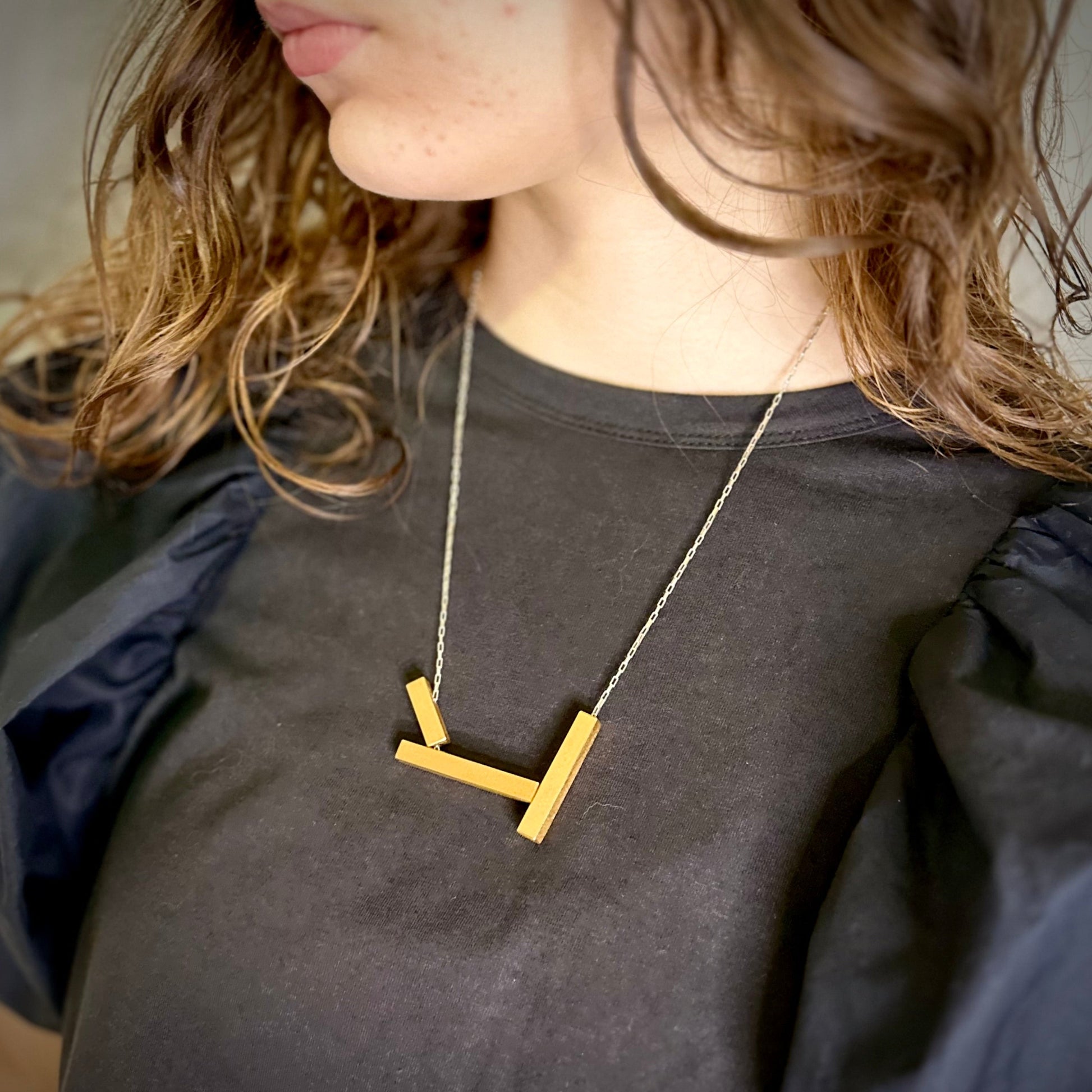 Architectural landslide necklace in gold with silver chain, worn long. 