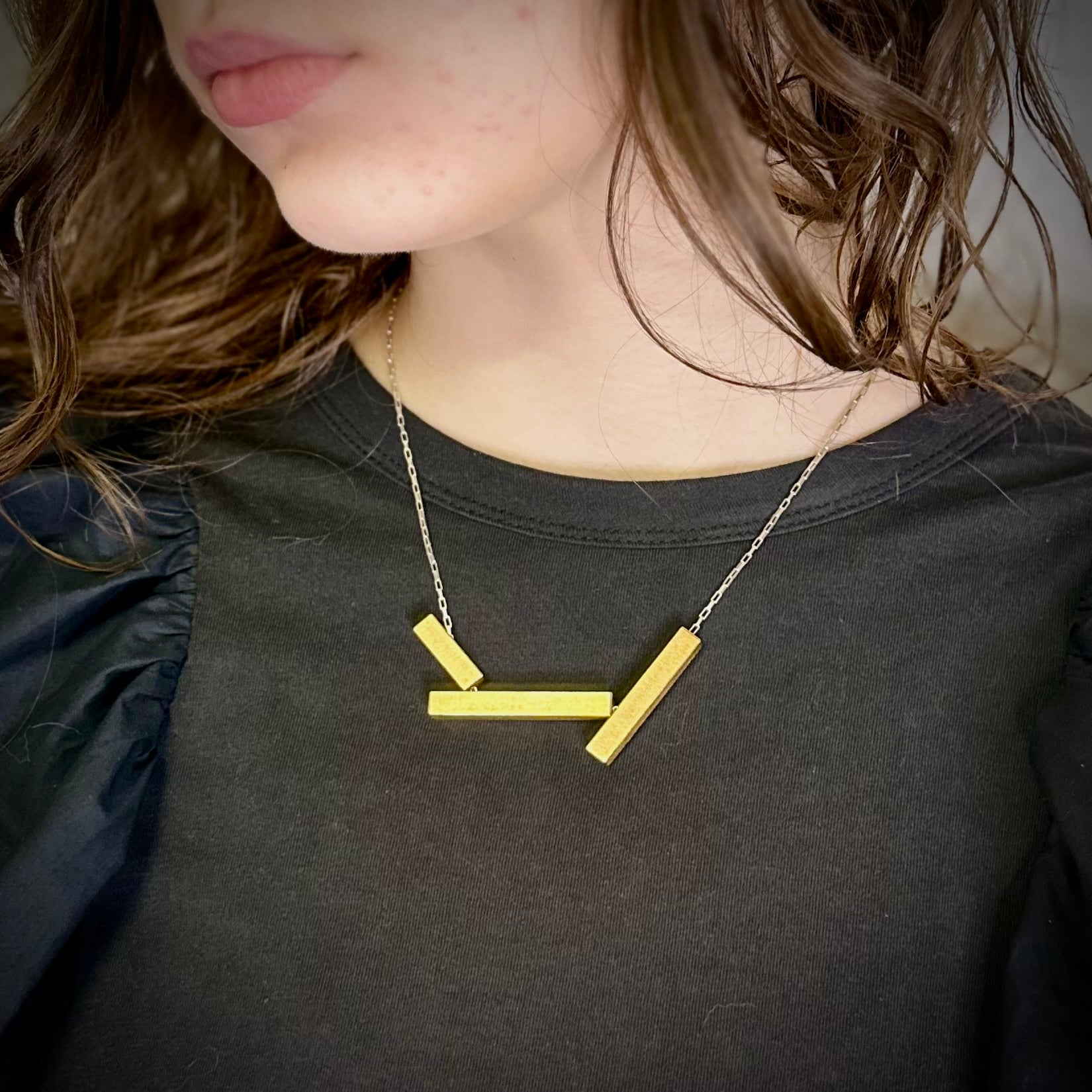 Geometric landslide necklace in gold with adjustable silver chain, worn short. 