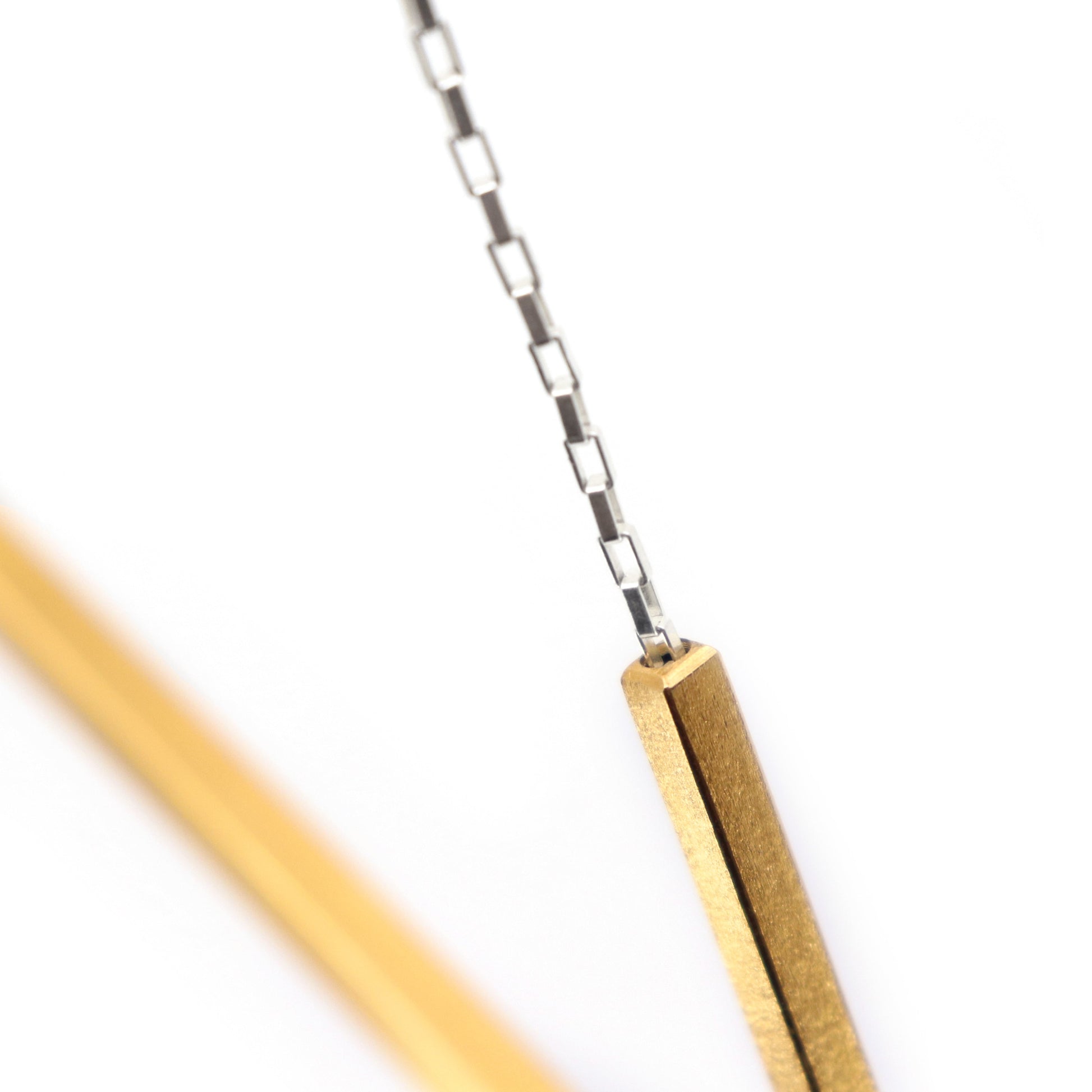 Close-up of a gold necklace component on a silver chain