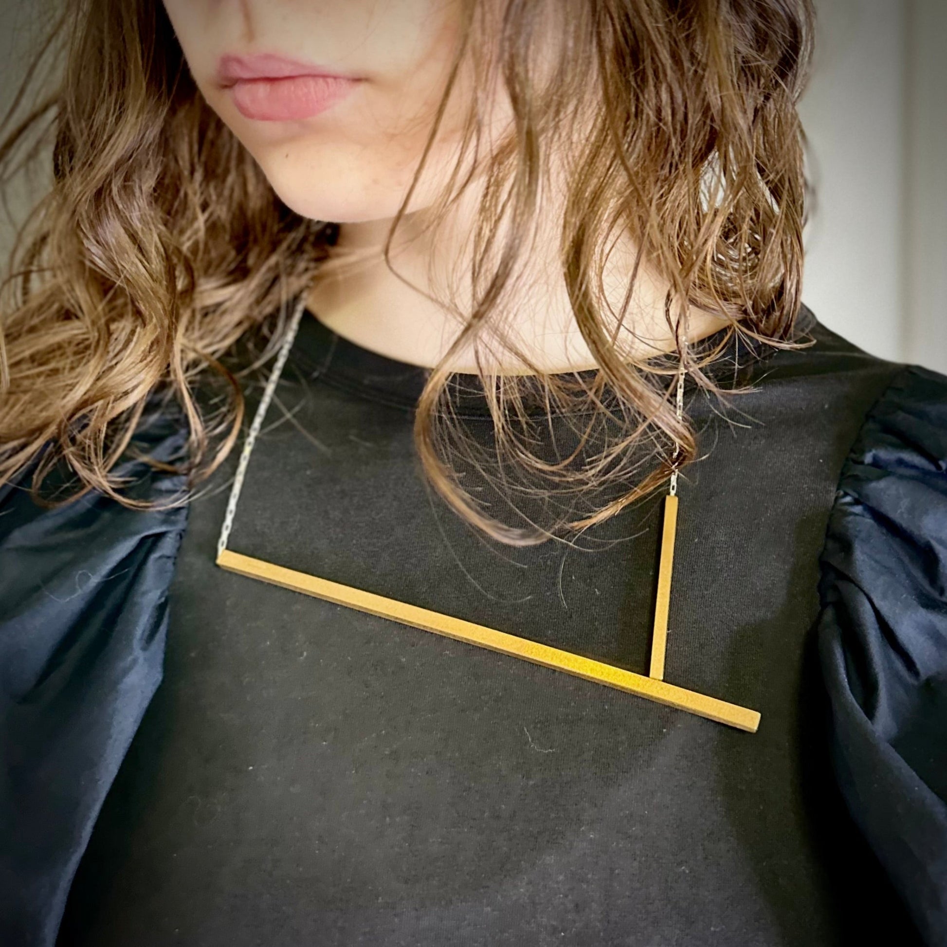 Person wearing a necklace with a rectangular pendant