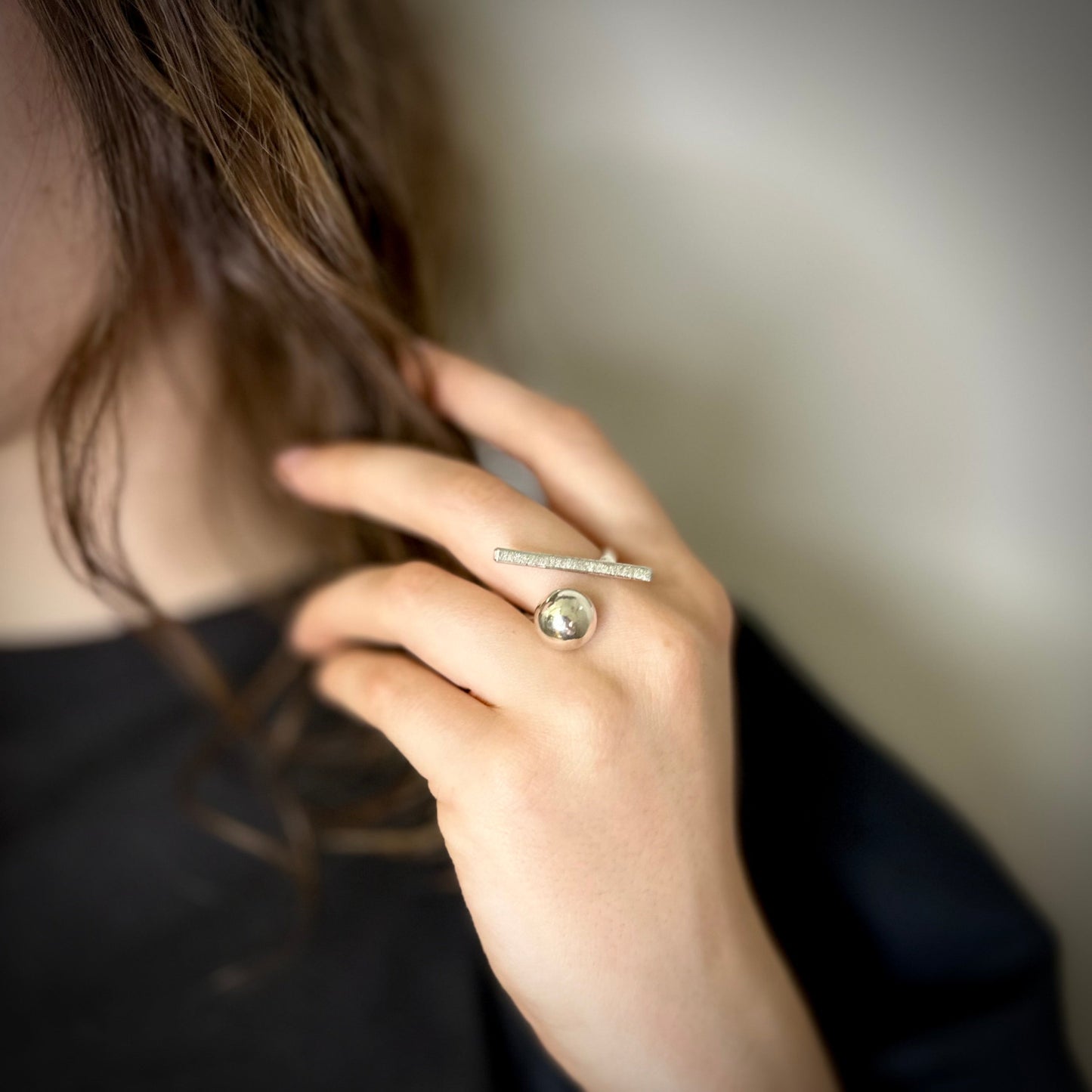 Close-up of a hand wearing a silver ring with a ball 