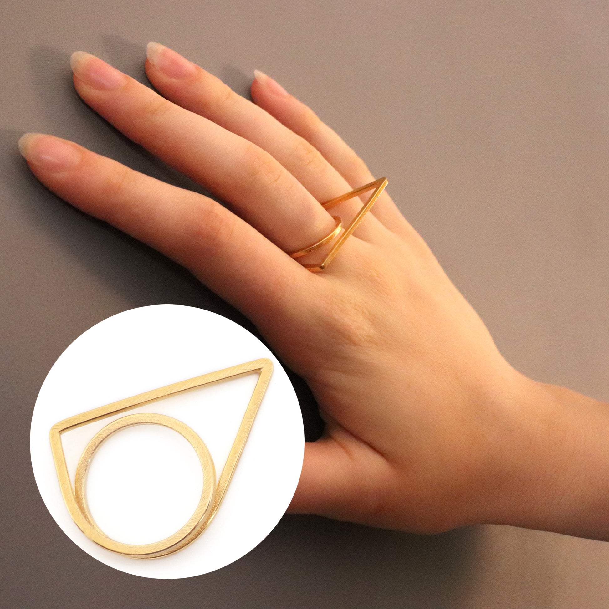 Hand wearing a gold geometric ring on a neutral background