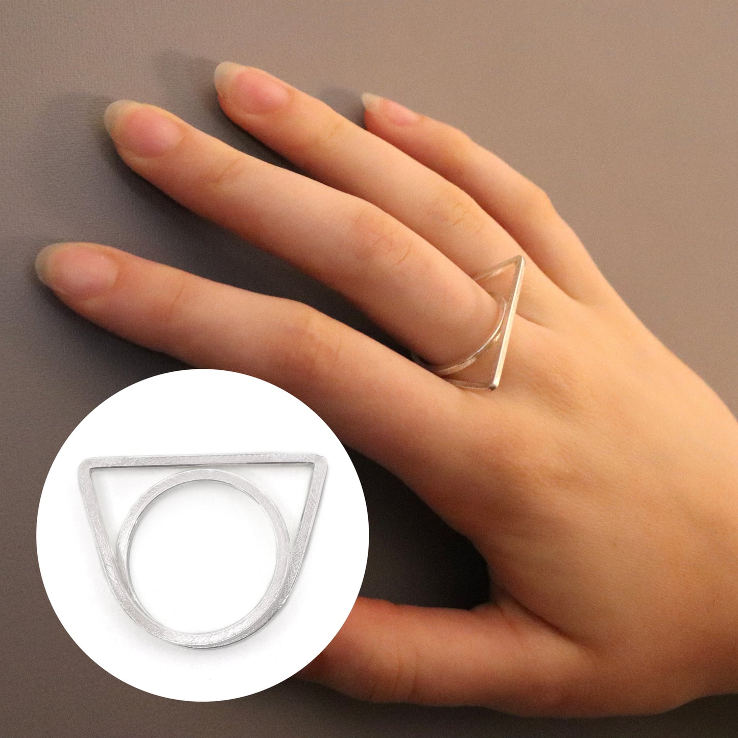 Hand wearing a triangular ring on a neutral background