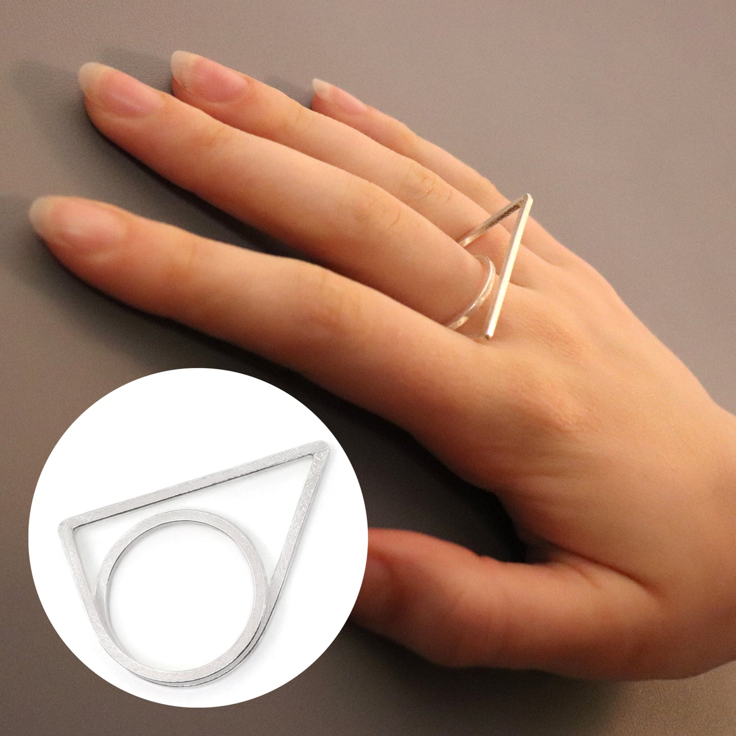 Hand wearing a gold triangle ring on a neutral background