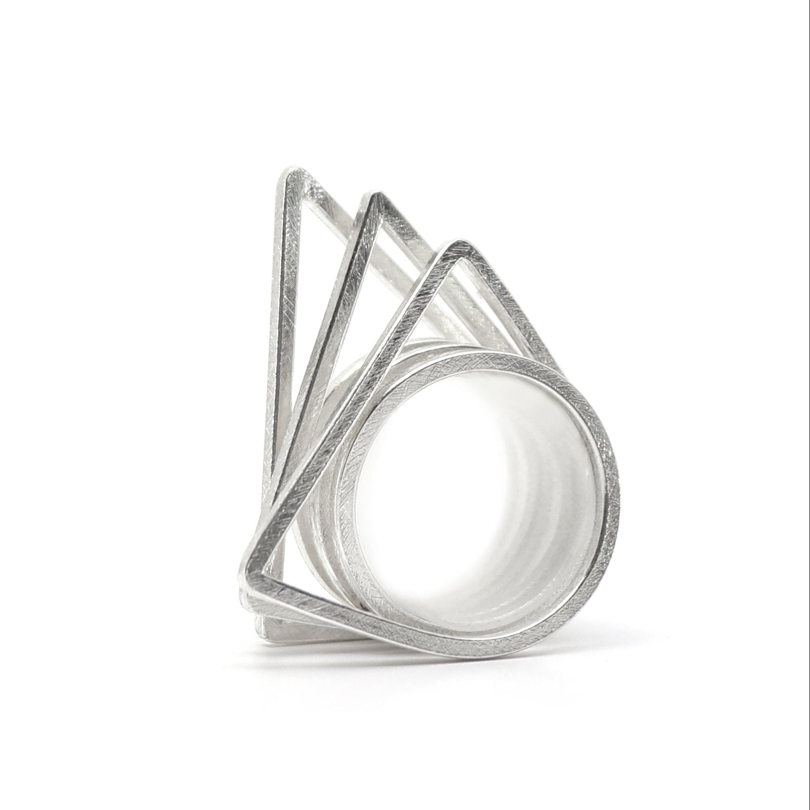 Set of three silver geometric rings on a white background