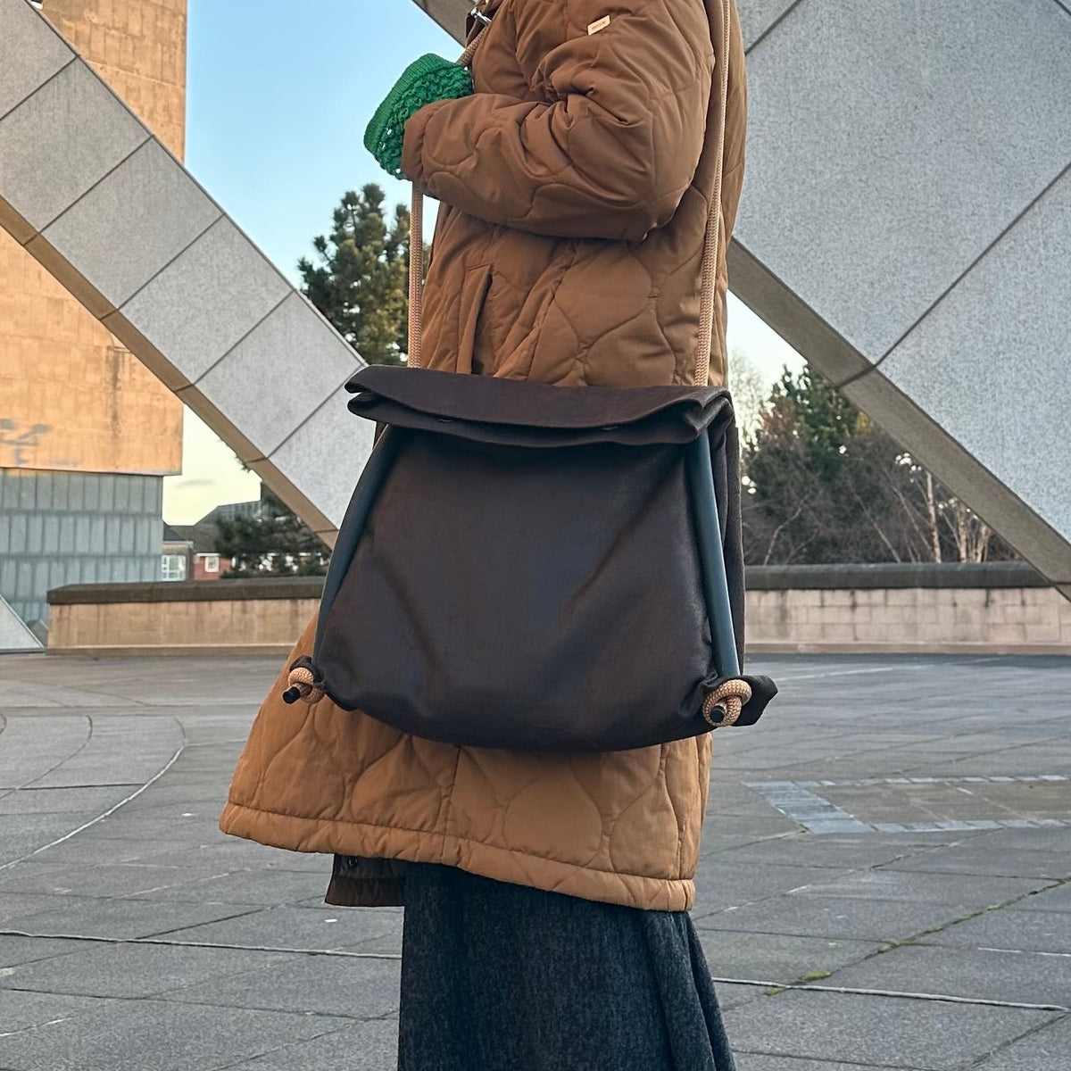 Brown Ditto backpack modelled by blond by modern brutalist architecture