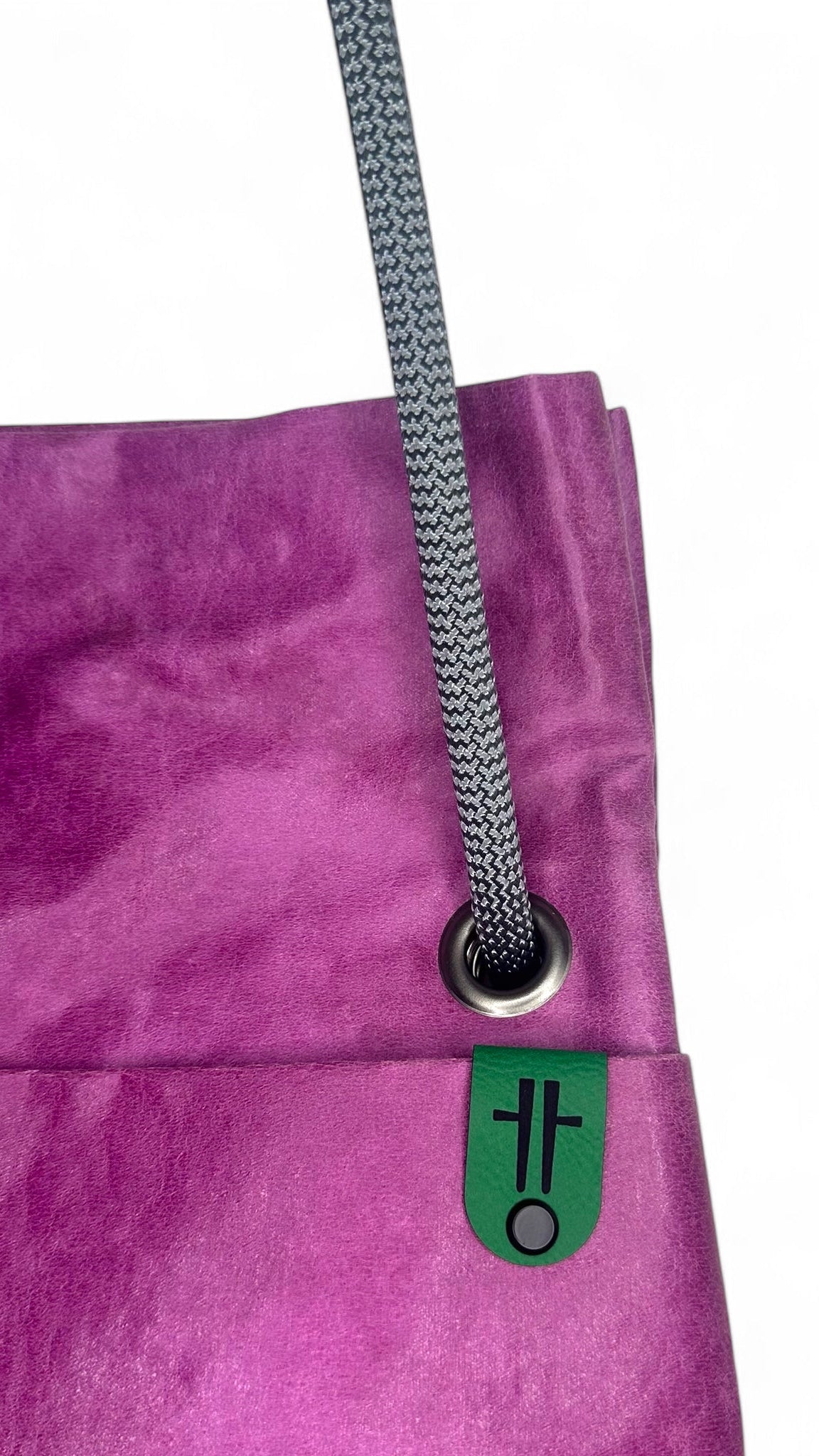 fuchsia sustainable commuter bag with reclaimed materials close up with logo