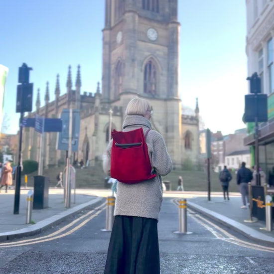 Ditto red crimson convertible bag going from back to shoulder with the Bombed Out Church in Liverpool