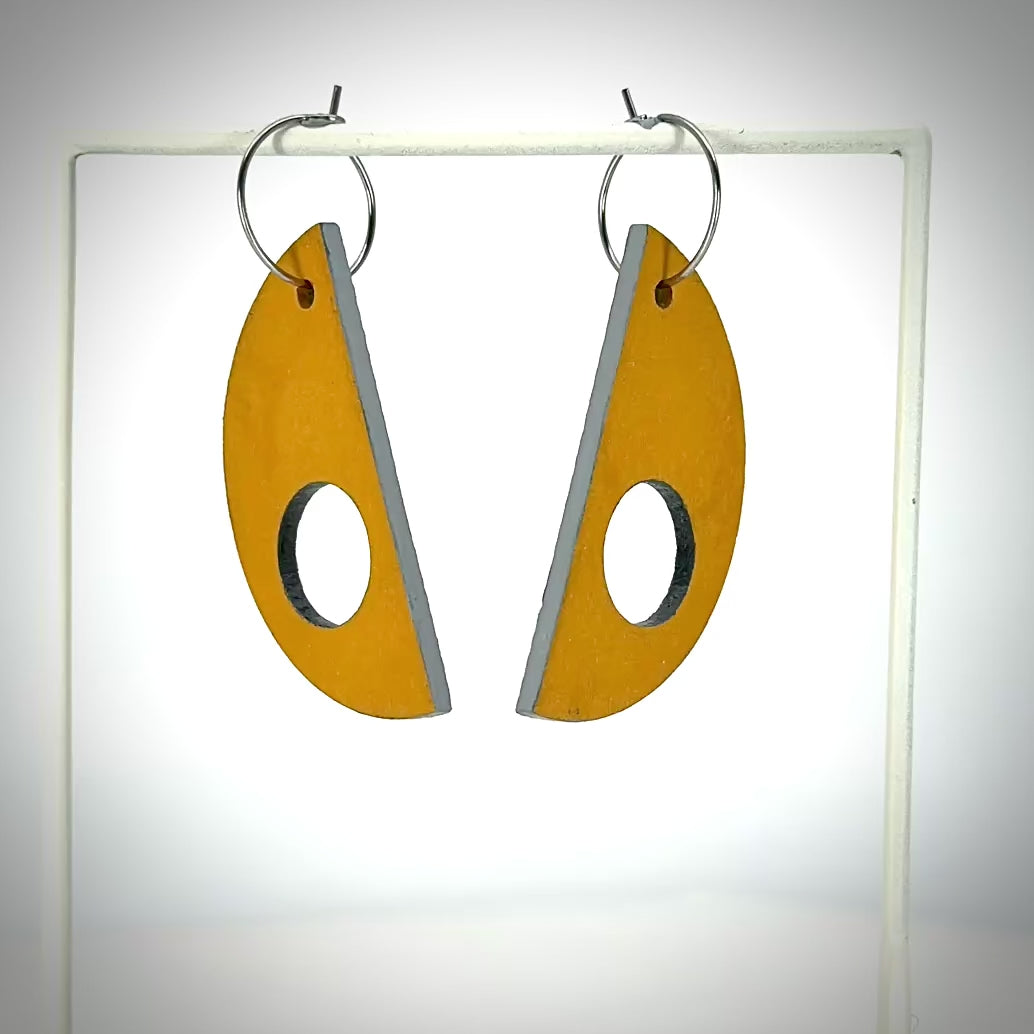 orange crescent moon shaped earring s hanging on small hoops rotating to expose the grey back