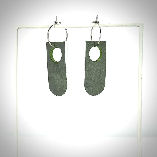 rotating grey and green earrings on an earring stand