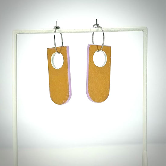 reversible orange and lilac linoleum earrings on stand and spinning around