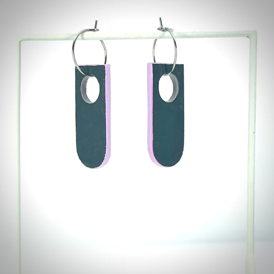 navy blue earrings with a pink back rotating on earring stand