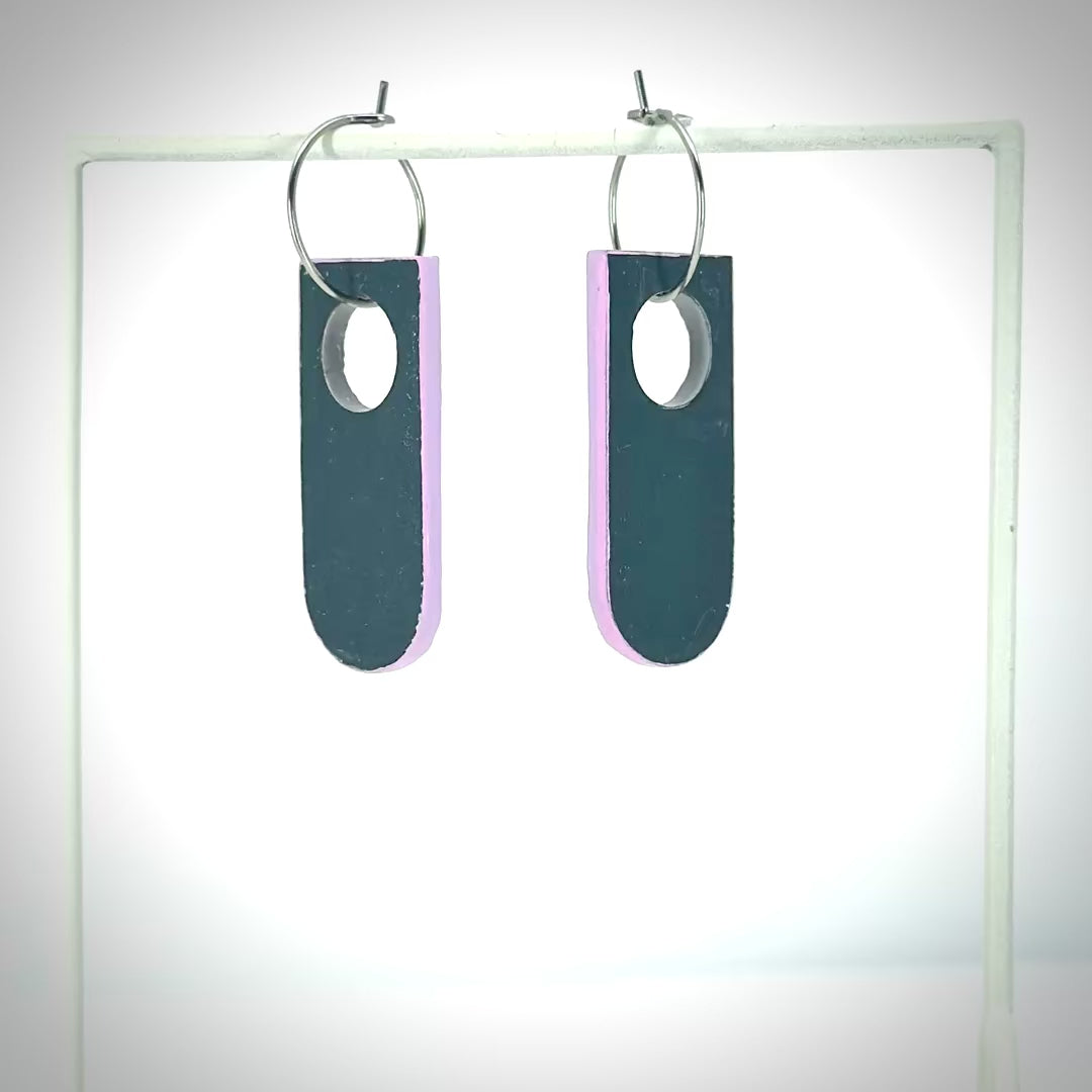 navy blue earrings with a pink back rotating on earring stand