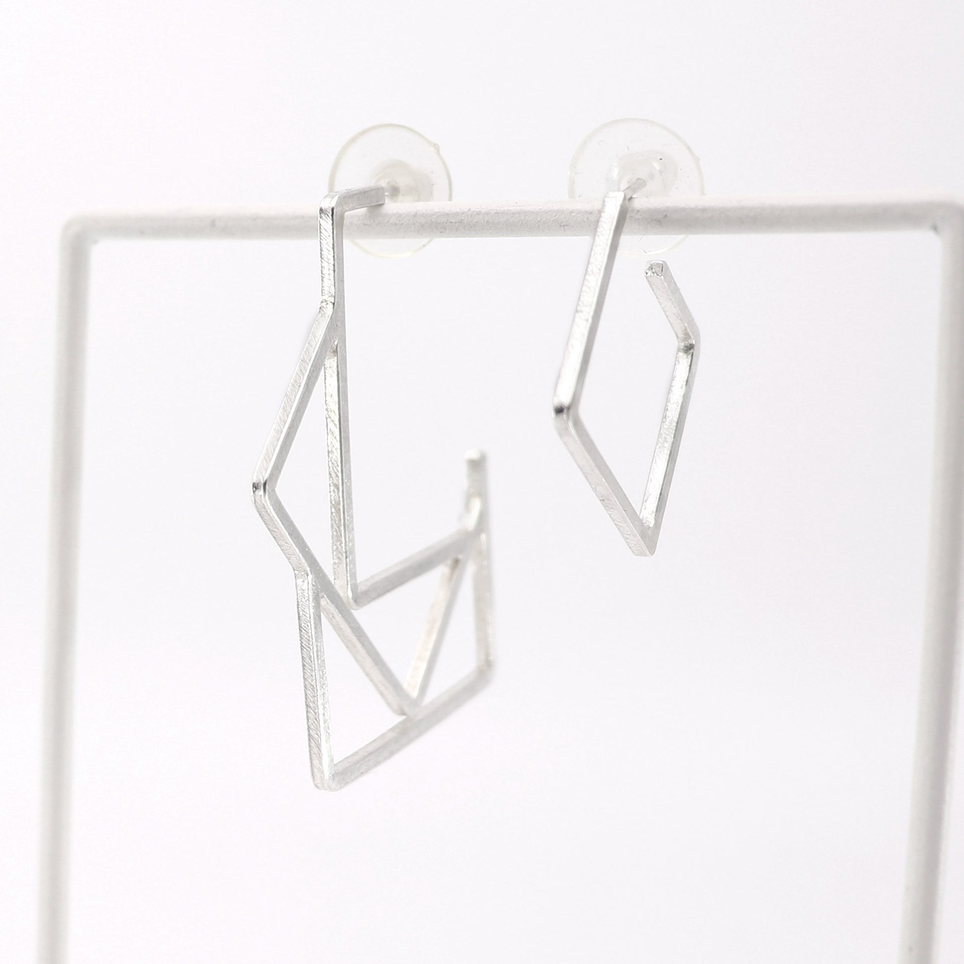 Silver geometric hoop earrings on a white background